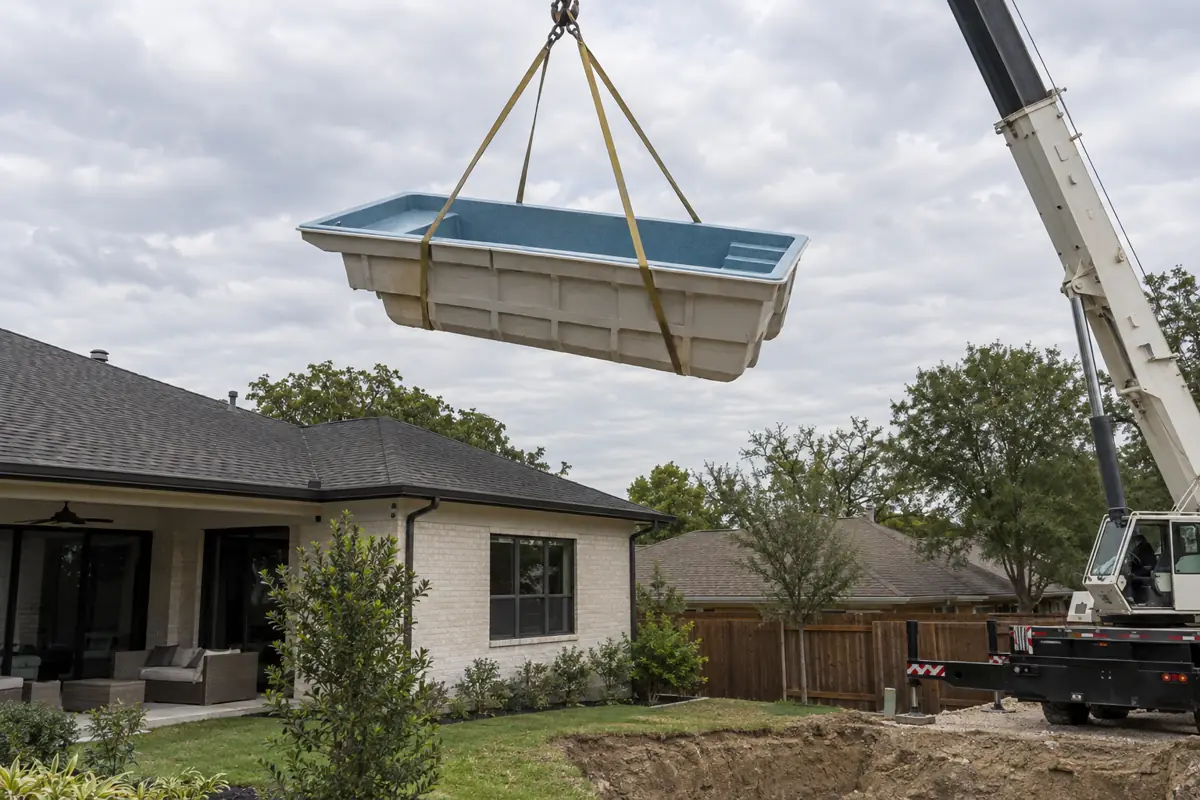 A one-piece shell lifted over a house by crane. Access, not pool size, sets this line of the budget.